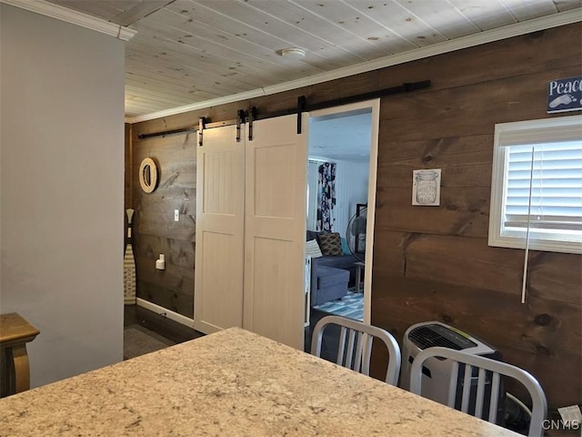 dining space with crown molding, a barn door, wooden ceiling, and wooden walls