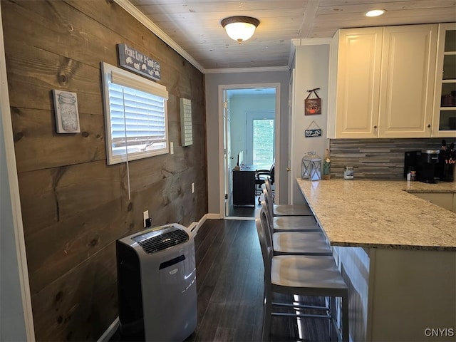 kitchen featuring a kitchen breakfast bar, white cabinetry, a wealth of natural light, and light stone counters