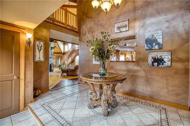 entrance foyer with a notable chandelier, a towering ceiling, and light tile flooring