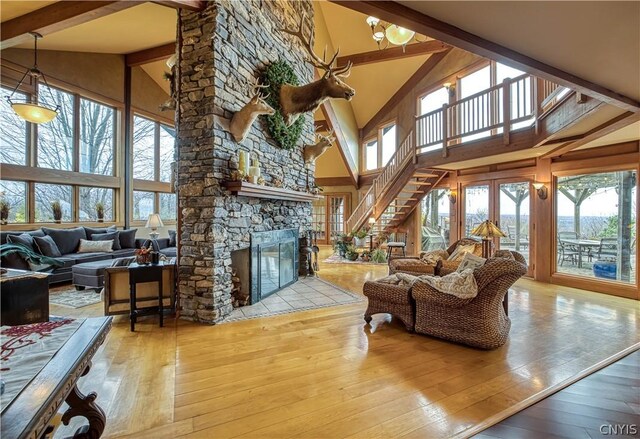 living room featuring a stone fireplace, high vaulted ceiling, beam ceiling, and hardwood / wood-style floors