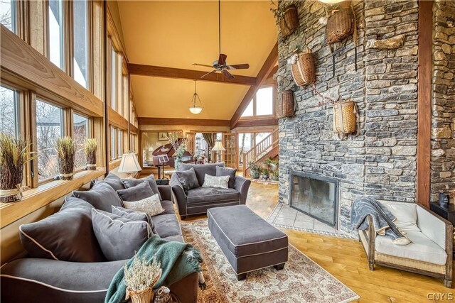 living room featuring high vaulted ceiling, a stone fireplace, plenty of natural light, and wood-type flooring