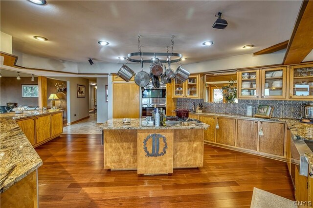 kitchen featuring a wealth of natural light, a center island, hardwood / wood-style flooring, and light stone countertops