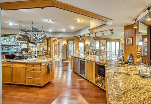 kitchen with a wealth of natural light, black microwave, wood-type flooring, and wine cooler