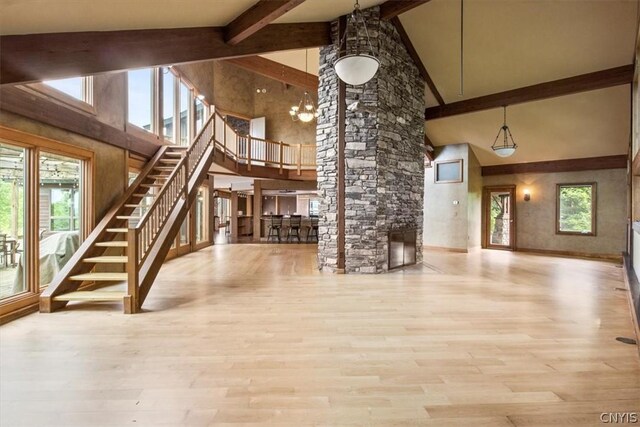 unfurnished living room featuring high vaulted ceiling, light hardwood / wood-style floors, and an inviting chandelier