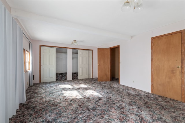 unfurnished bedroom featuring beamed ceiling, carpet floors, and a closet