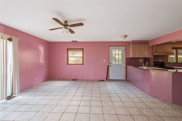 kitchen featuring plenty of natural light, sink, range, and light tile patterned floors