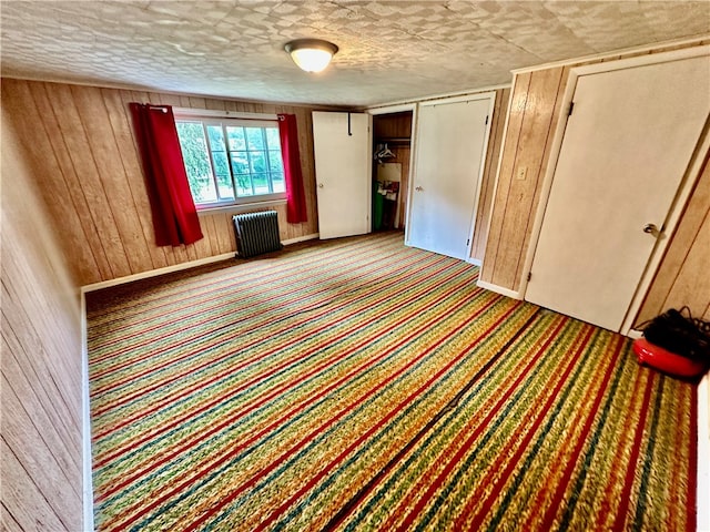 spare room featuring wooden walls and radiator heating unit