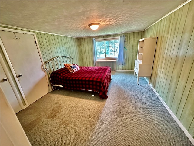 bedroom featuring wood walls, a textured ceiling, and carpet flooring