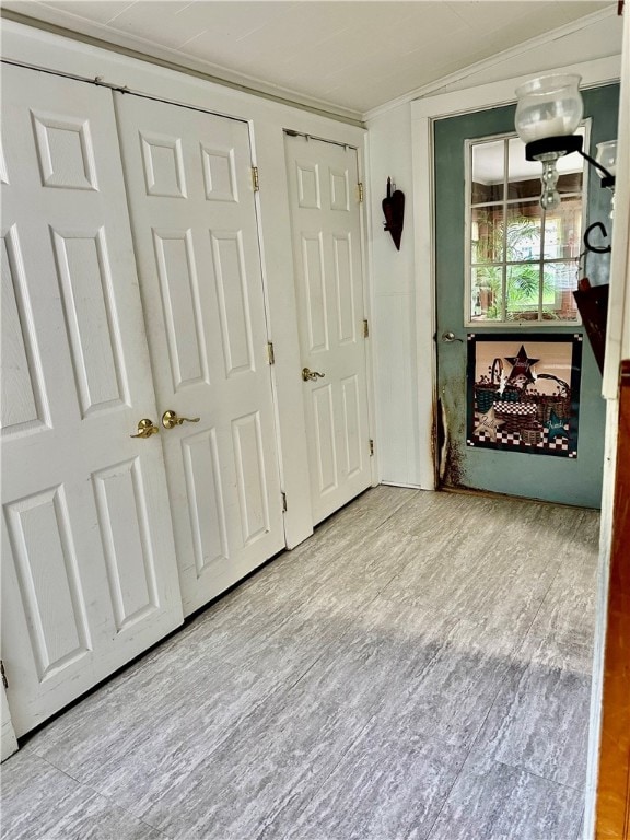 hall with light wood-type flooring and lofted ceiling