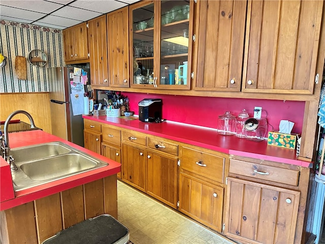 kitchen with a drop ceiling, sink, and stainless steel refrigerator