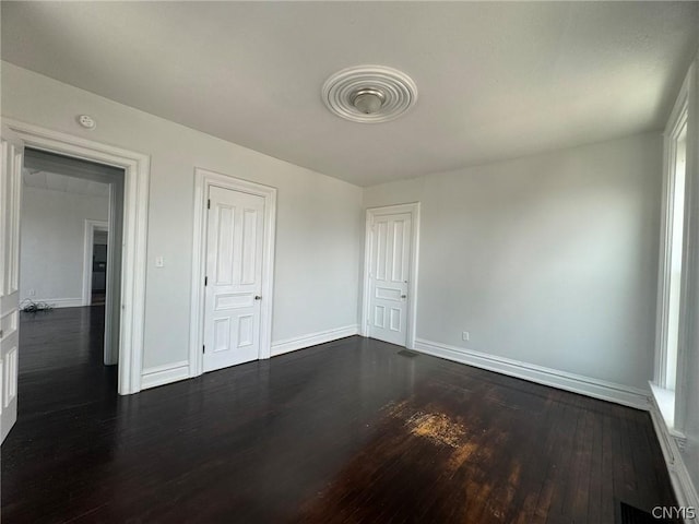 unfurnished bedroom with dark wood-type flooring and baseboards