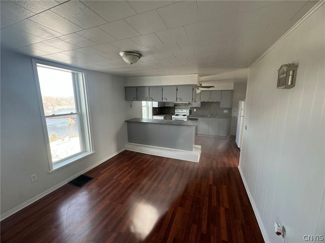 kitchen featuring dark wood-style floors, visible vents, gray cabinetry, a peninsula, and baseboards