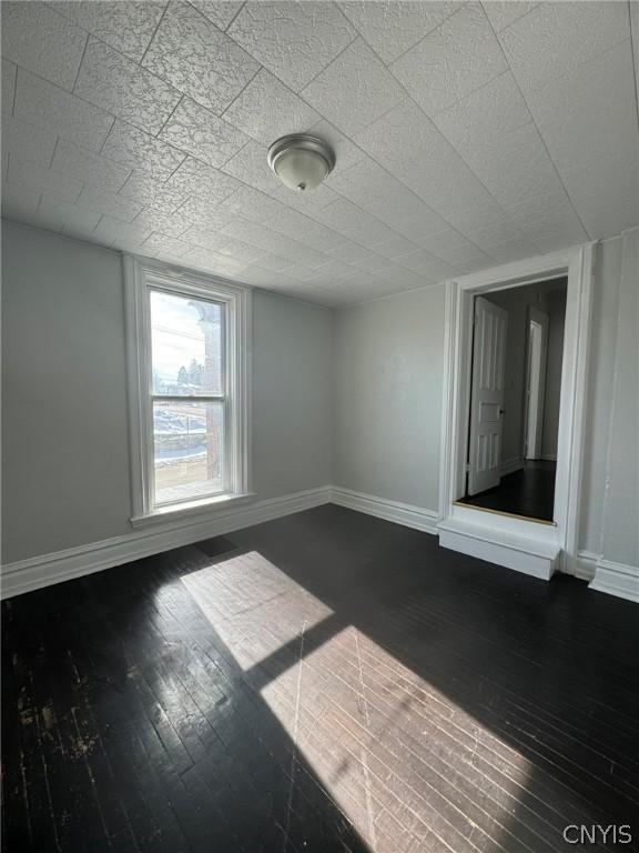 spare room with dark wood finished floors, a textured ceiling, and baseboards