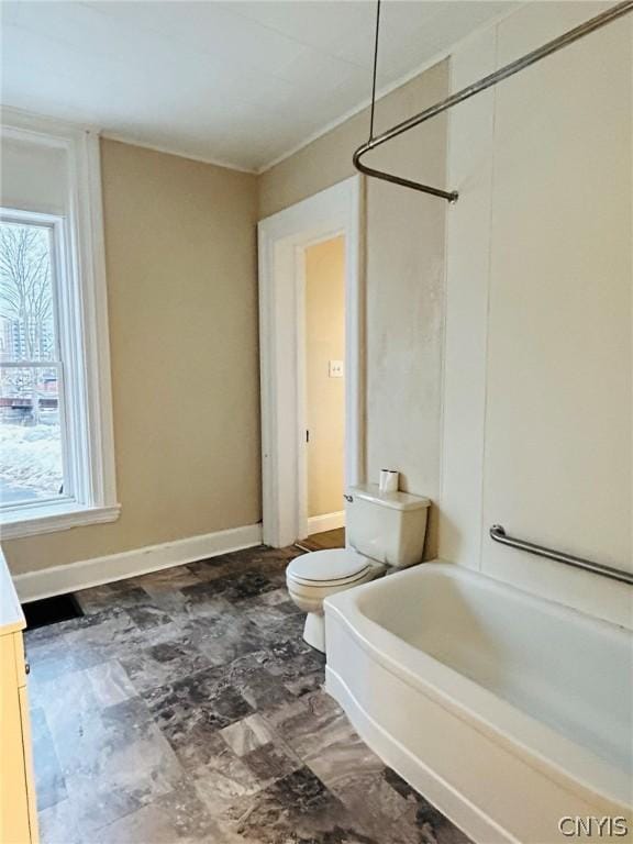 bathroom with baseboards, shower / tub combination, and toilet