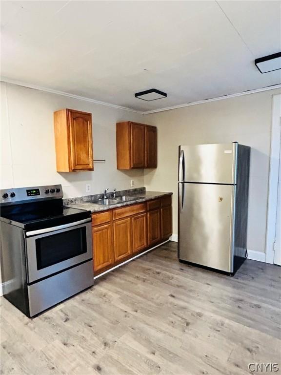 kitchen featuring appliances with stainless steel finishes, light hardwood / wood-style floors, sink, and ornamental molding