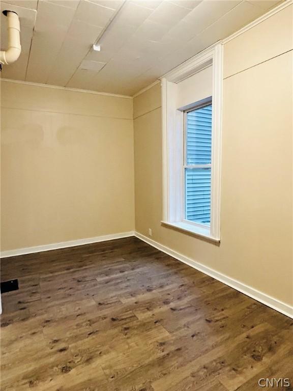 empty room featuring baseboards and dark wood-type flooring