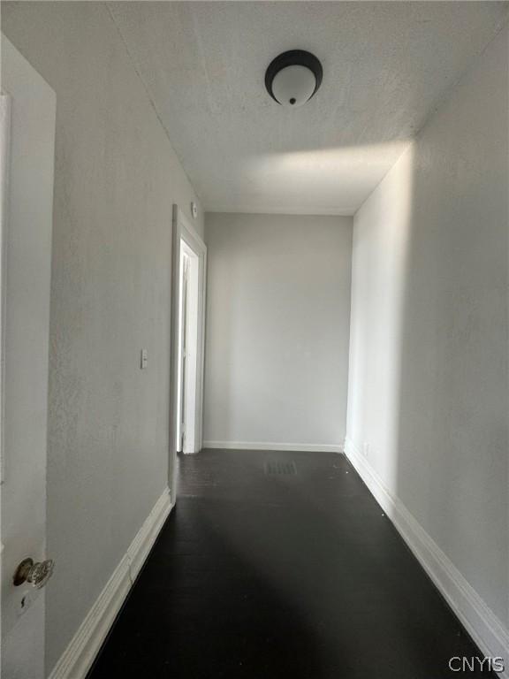 hallway with baseboards and a textured ceiling