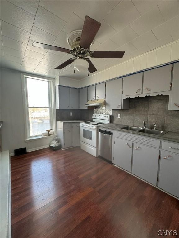 kitchen with dark wood finished floors, white electric stove, stainless steel dishwasher, a sink, and under cabinet range hood