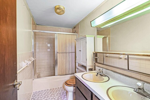 full bathroom with vanity, shower / bath combination with glass door, tile walls, tile patterned flooring, and toilet