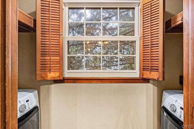 clothes washing area with a healthy amount of sunlight, washer and clothes dryer, and cabinets