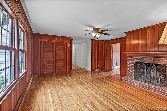 unfurnished living room featuring plenty of natural light, ceiling fan, light wood-type flooring, and a fireplace