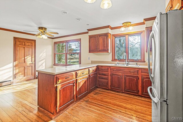 kitchen featuring kitchen peninsula, stainless steel refrigerator, plenty of natural light, and sink