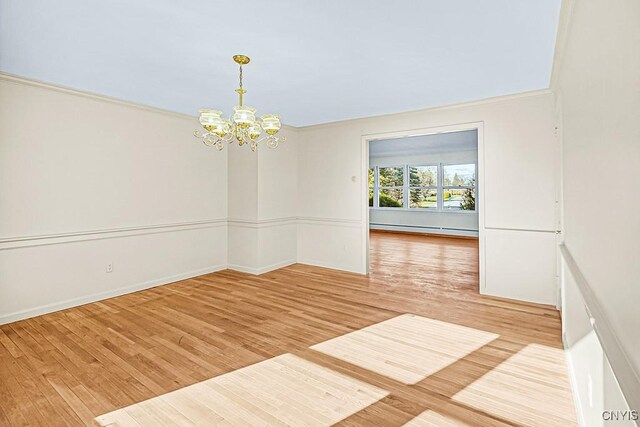 unfurnished room with a chandelier, hardwood / wood-style flooring, crown molding, and a baseboard heating unit