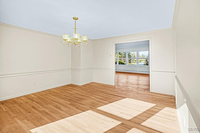 spare room with a notable chandelier, wood-type flooring, and a baseboard heating unit