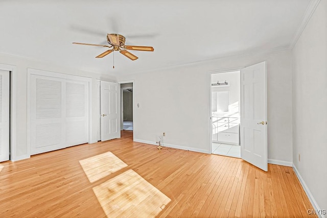 unfurnished bedroom with ceiling fan, hardwood / wood-style floors, connected bathroom, ornamental molding, and multiple closets