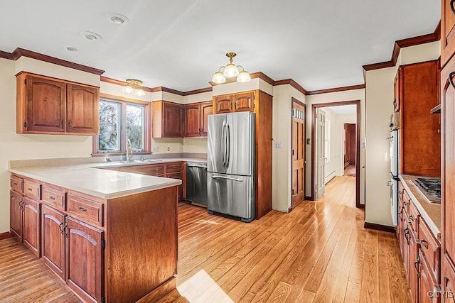 kitchen featuring appliances with stainless steel finishes, sink, light hardwood / wood-style floors, kitchen peninsula, and crown molding