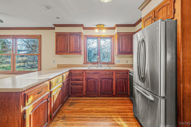 kitchen featuring sink, light hardwood / wood-style flooring, stainless steel fridge, ornamental molding, and kitchen peninsula