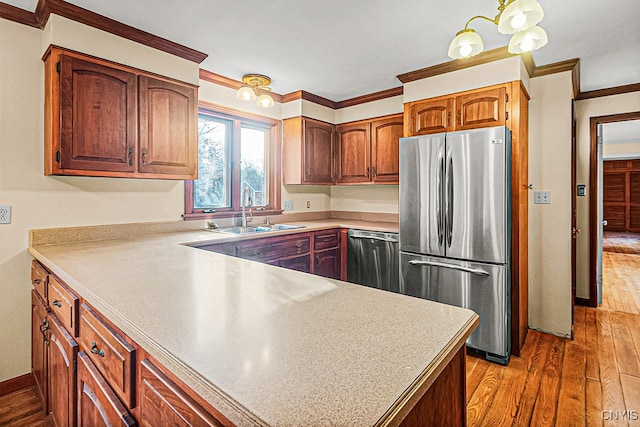 kitchen with hardwood / wood-style floors, appliances with stainless steel finishes, crown molding, and sink