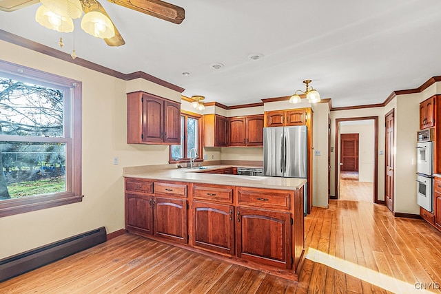 kitchen featuring a baseboard heating unit, sink, light hardwood / wood-style floors, kitchen peninsula, and stainless steel refrigerator