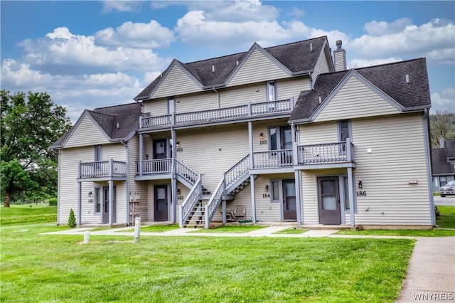 rear view of house with a lawn and a balcony