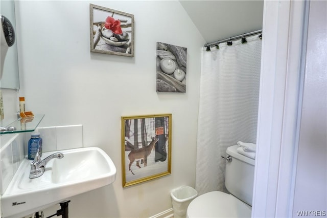 bathroom featuring vaulted ceiling, toilet, and sink