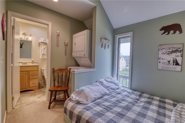 carpeted bedroom with ensuite bath, stacked washer / dryer, lofted ceiling, and sink