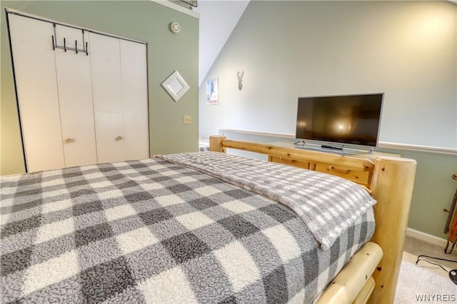 carpeted bedroom featuring vaulted ceiling and a closet