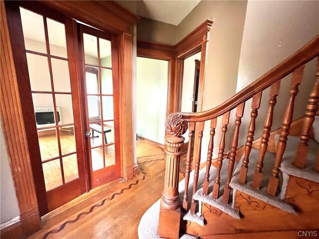 stairway featuring plenty of natural light, french doors, and wood-type flooring