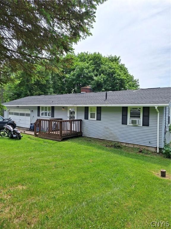 view of front of house with a garage, a deck, and a front yard