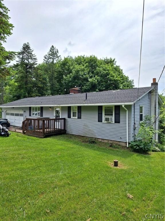 single story home featuring a front yard, a deck, and a garage