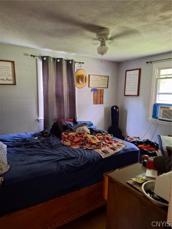 bedroom with ceiling fan, cooling unit, and a textured ceiling