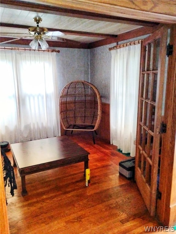 living area featuring beam ceiling, ceiling fan, and hardwood / wood-style floors