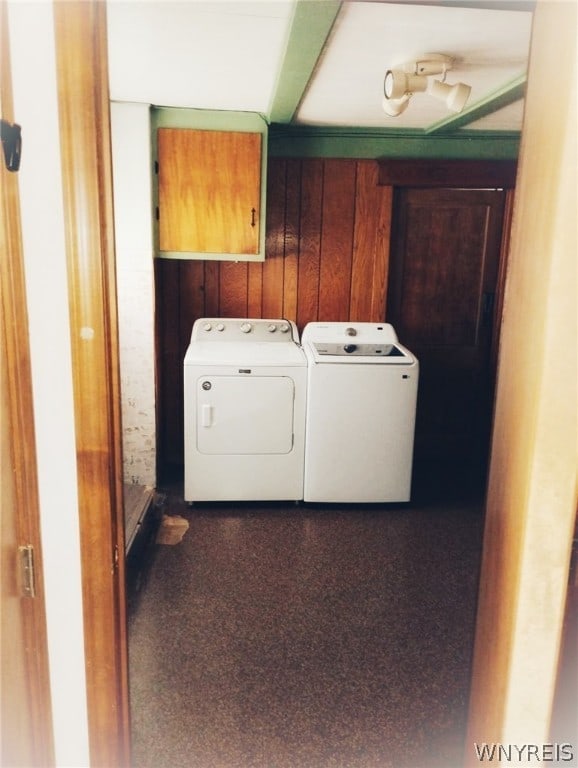 laundry room featuring wooden walls, washer and dryer, and dark carpet