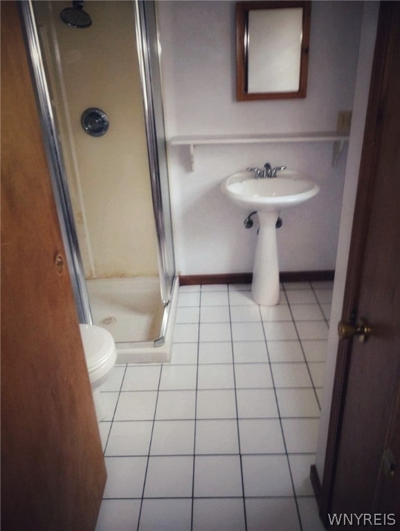 bathroom featuring toilet, tile floors, and a shower with door