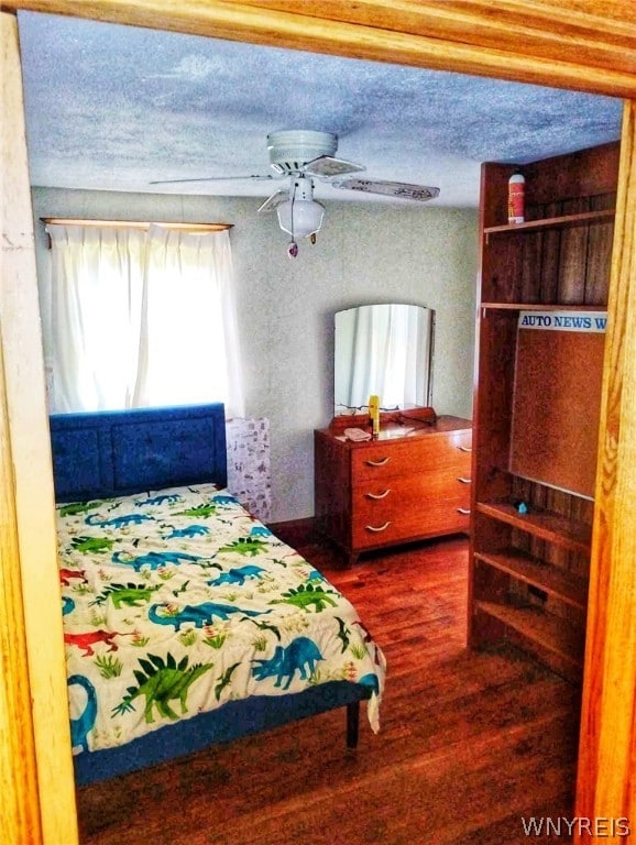 bedroom with ceiling fan, a textured ceiling, and dark wood-type flooring