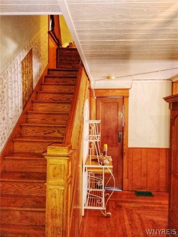 stairs with wooden walls and hardwood / wood-style flooring