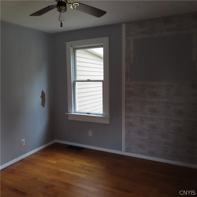 spare room featuring a healthy amount of sunlight, ceiling fan, and dark wood-type flooring