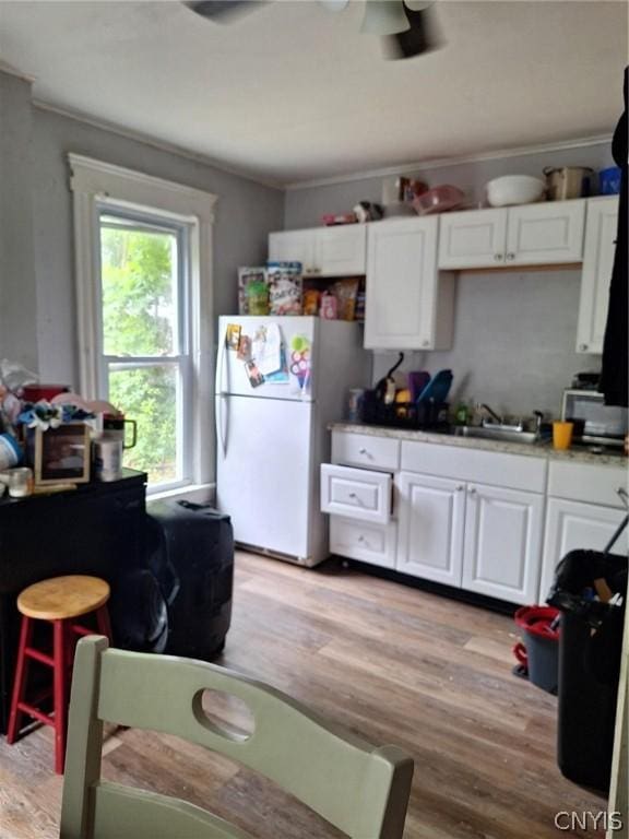 kitchen with white refrigerator, white cabinetry, and a healthy amount of sunlight