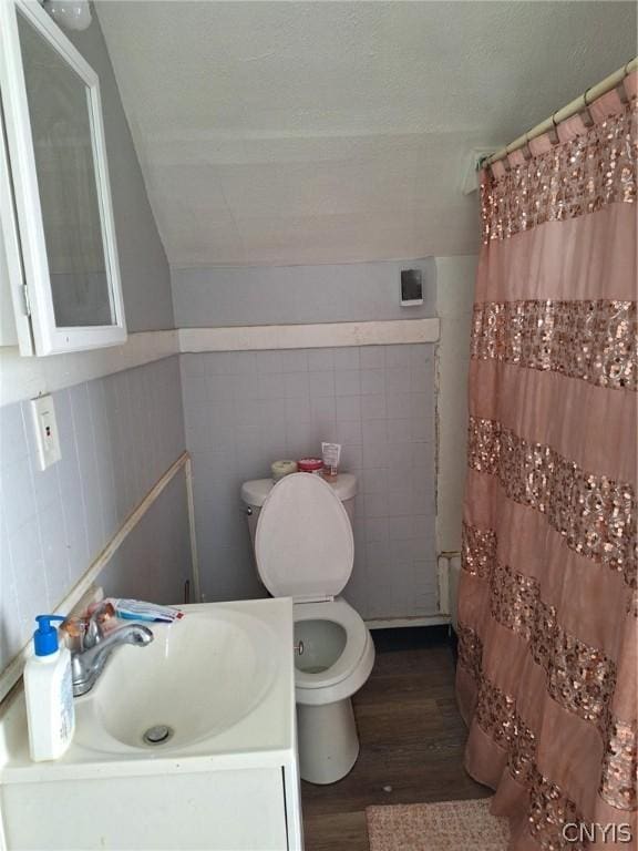 full bathroom featuring wood-type flooring, vaulted ceiling, toilet, vanity, and shower / tub combo