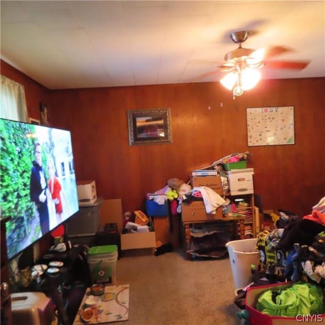 recreation room with wood walls, carpet, and ceiling fan